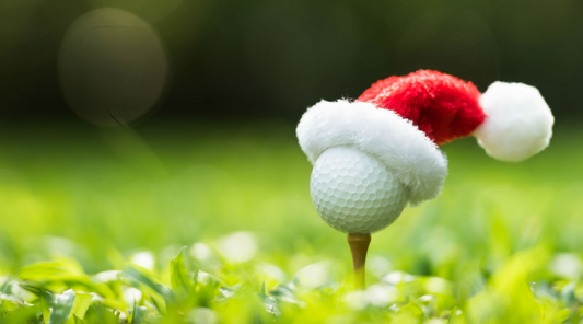 Image of a golf ball on a tee wearing a Santa hat
