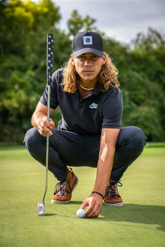 A lifestyle image of a golfer aligning his golf ball with his putter in hand, highlighting the Sweetrollz grip that is on it