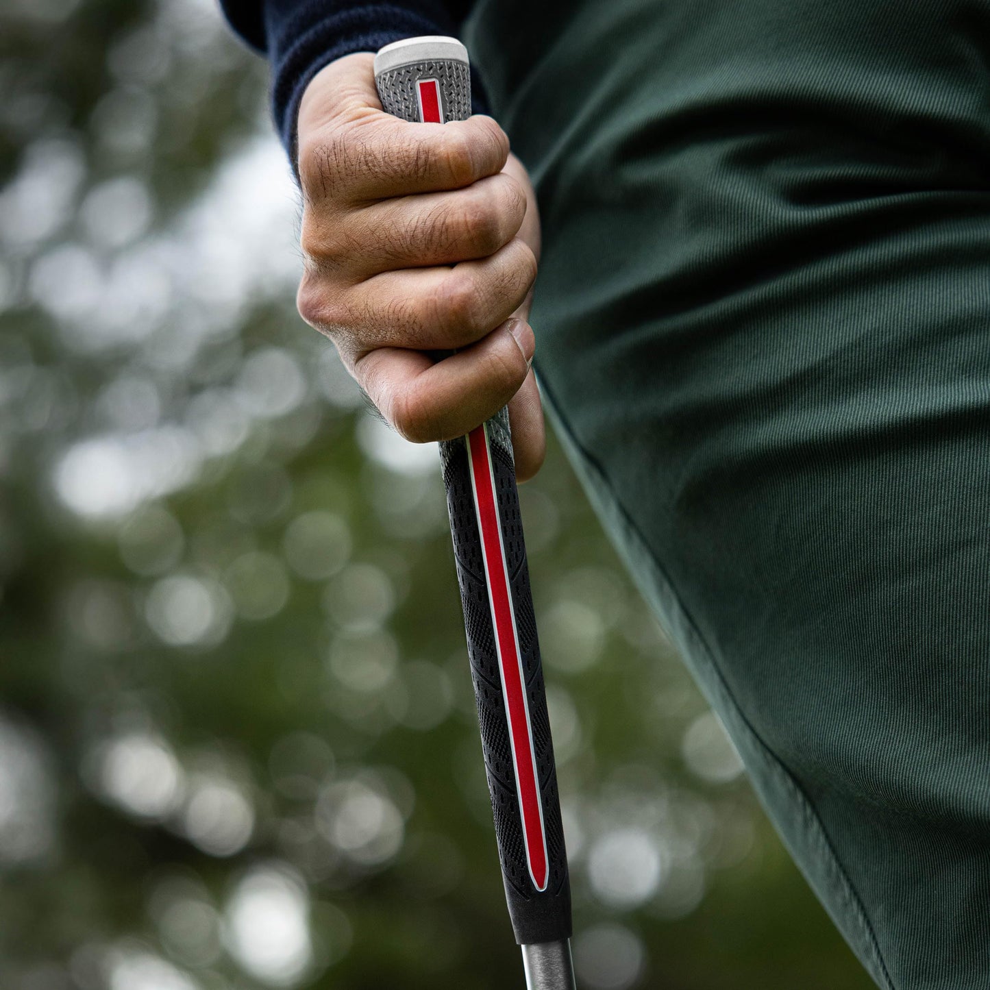 Close-up of a hand holding a golf club with a with a Golf Pride Align Grip and a blurred green background