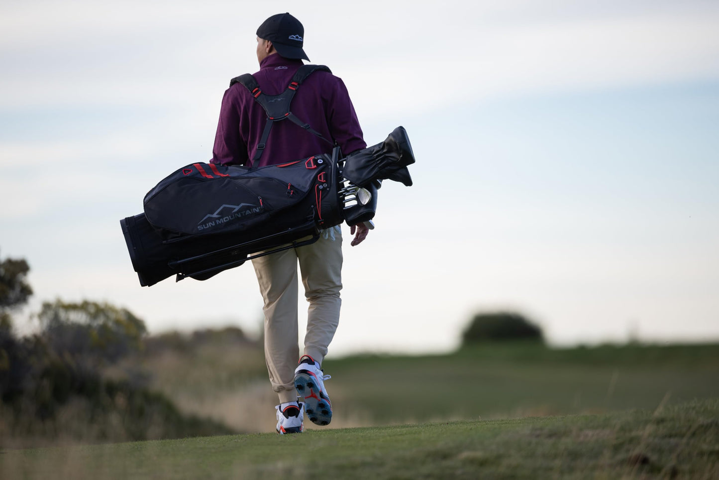 Person walking on a golf course carrying a golf bag