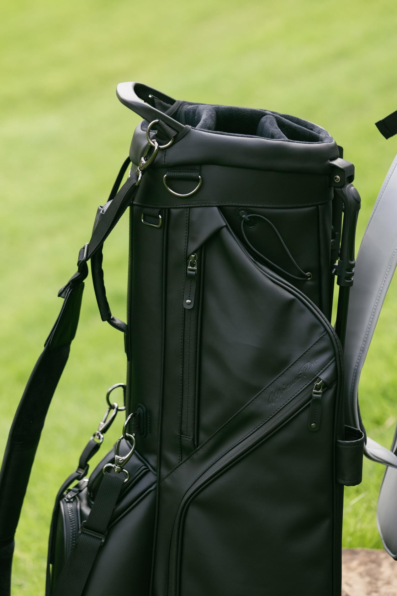 Black golf bag on a golf cart with grass in the background