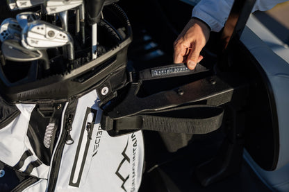 Close-up of a golf bag with clubs attached, held by a person.