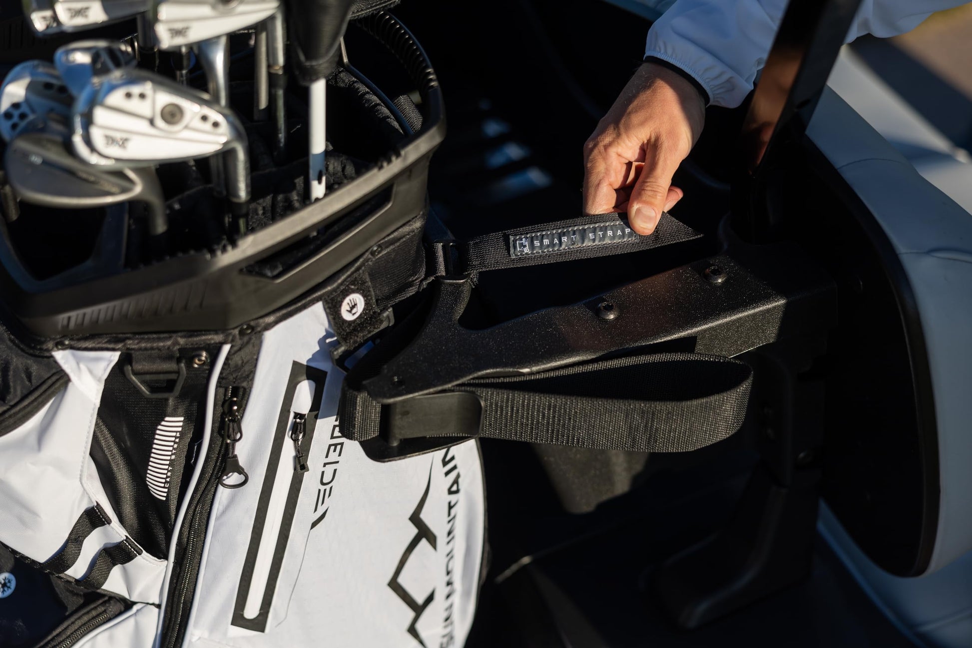 Close-up of a golf bag with clubs attached, held by a person.