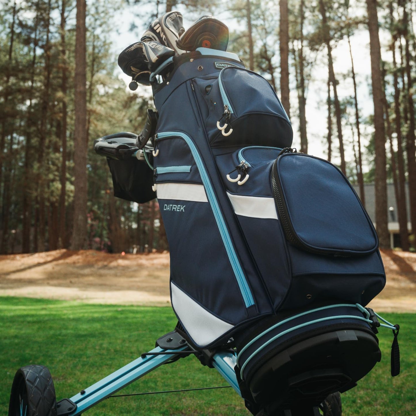 Navy golf bag with white stripe on a golf cart in a forest setting