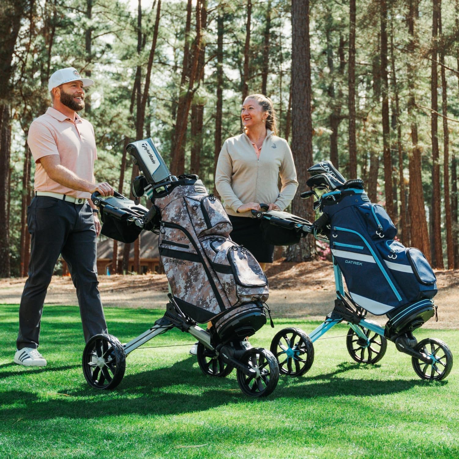 Two people pushing golf carts with golf bags on a golf course.