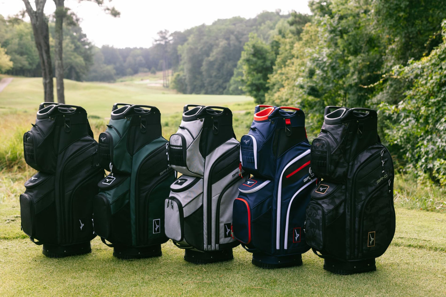 Collection of golf bags on a grassy area with trees in the background