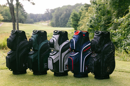 Collection of golf bags on a grassy area with trees in the background
